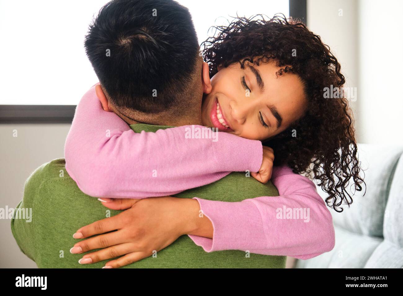 Dominikanerin umarmt ihren chinesischen Freund zu Hause. Stockfoto