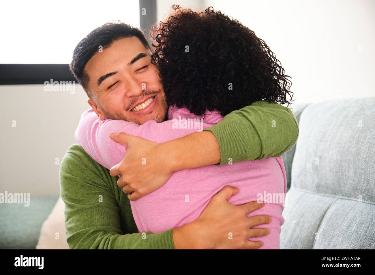 Ein chinesischer Mann umarmt seine dominikanische Freundin zu Hause. Stockfoto
