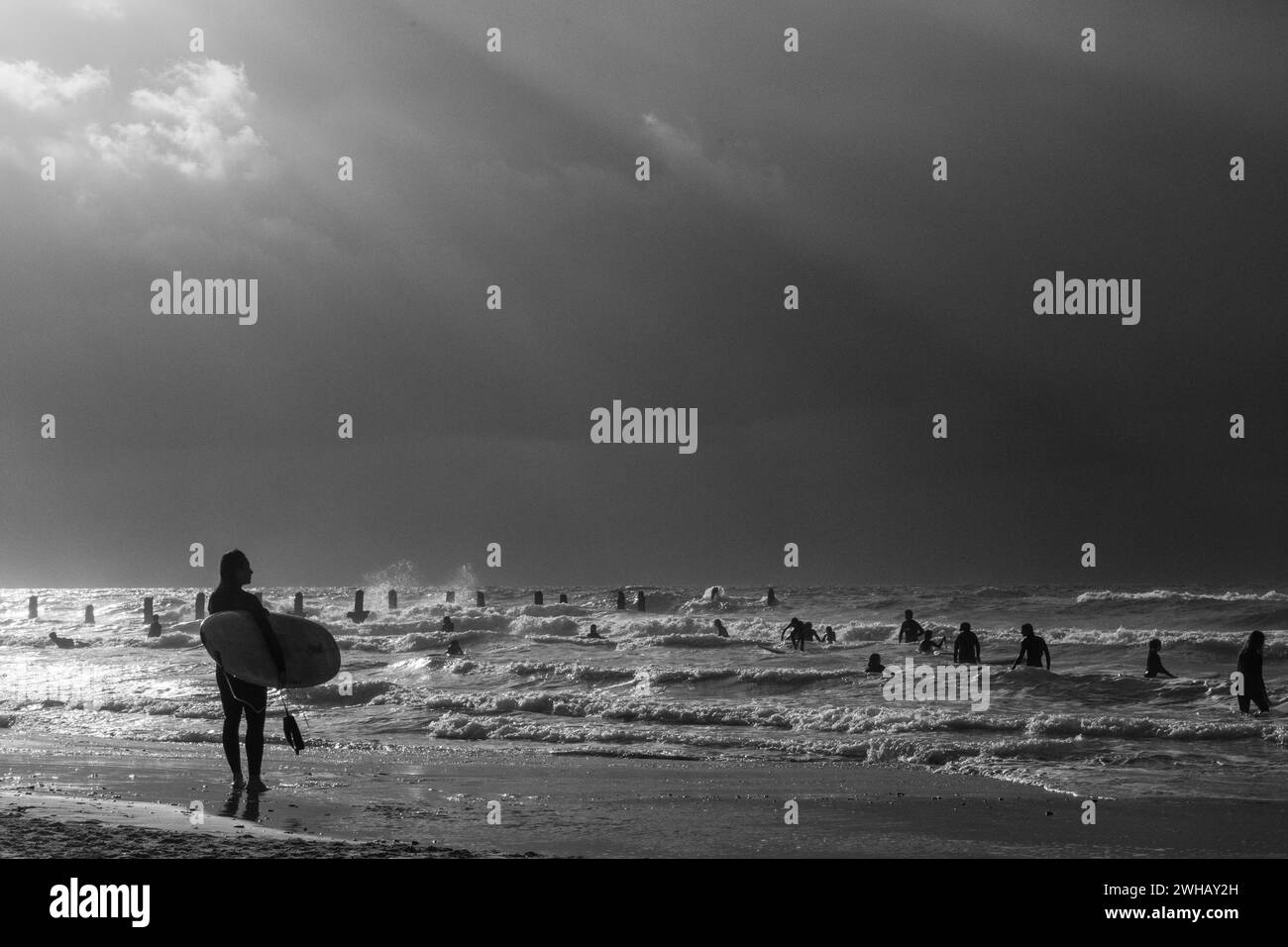 Wassersportbegeisterte mit verschiedenen Formen des Surfens und Segelns in Schwarzweiß in der Abenddämmerung fotografiert am Strand von Beit Yanai, Israel Beit Yanai Stockfoto