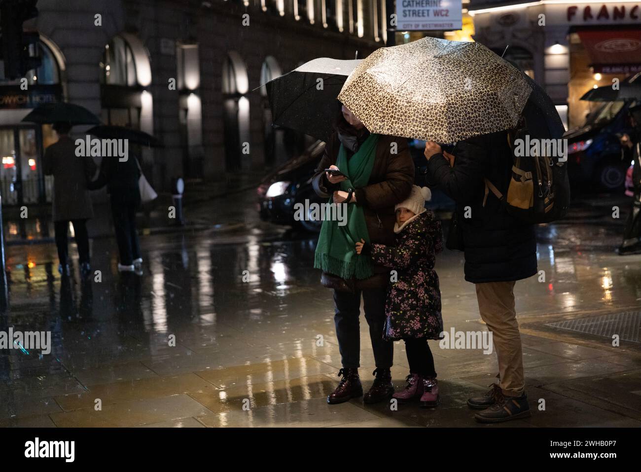 Touristen mit Regenschirmen an einer verregneten Winternacht in Aldwych, Londons Theaterviertel im West End, London, England, Großbritannien Stockfoto