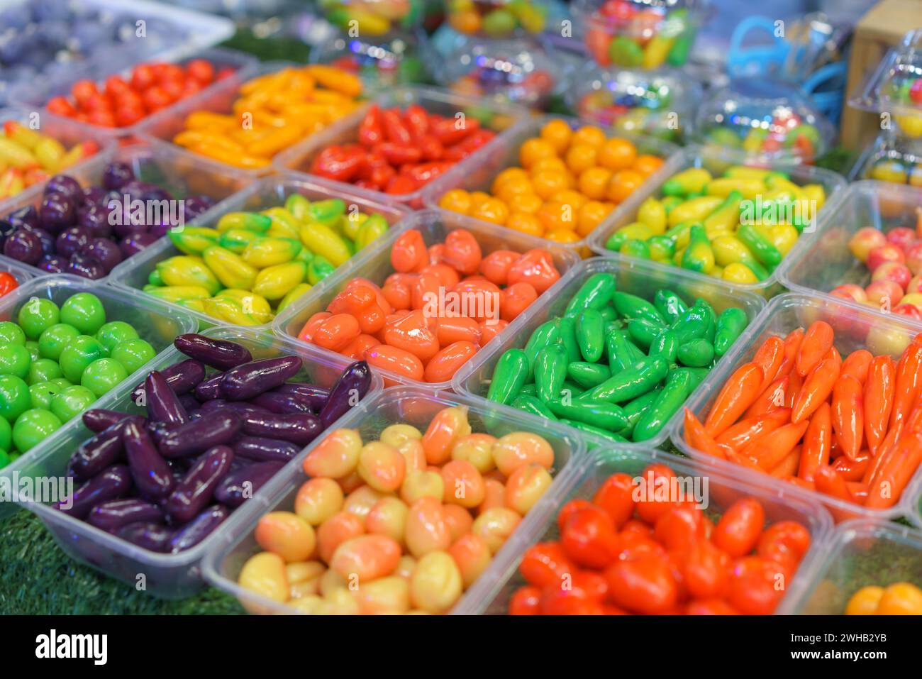 Eine Auswahl an fruchtförmigen Mung Beans lebhaften thailändischen Desserts, die an Miniatur-Obst und -Gemüse erinnern, werden in klaren Behältern im ausgestellt Stockfoto