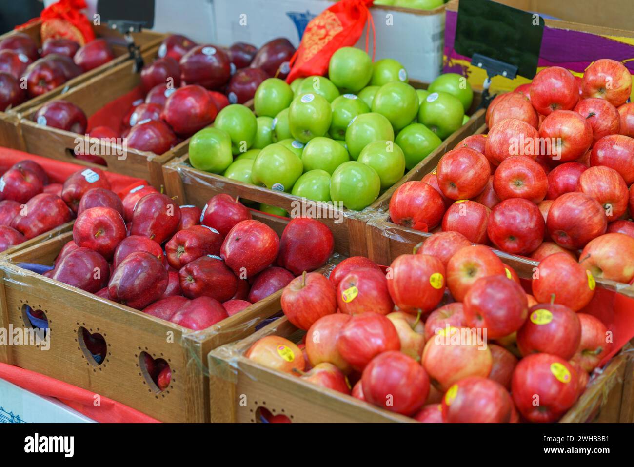 Holzkisten gefüllt mit einer Vielzahl von frischen roten und grünen Äpfeln auf einem lokalen Bauernmarkt, auf dem biologische und gesunde Produkte präsentiert werden Stockfoto