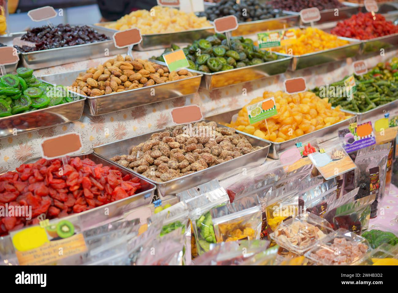 Lebendige und farbenfrohe Auswahl an getrockneten Früchten und Nüssen, die in Metallschalen auf einem Markt präsentiert werden und die Vielfalt und Attraktivität von gesunden Snack Optio unterstreichen Stockfoto