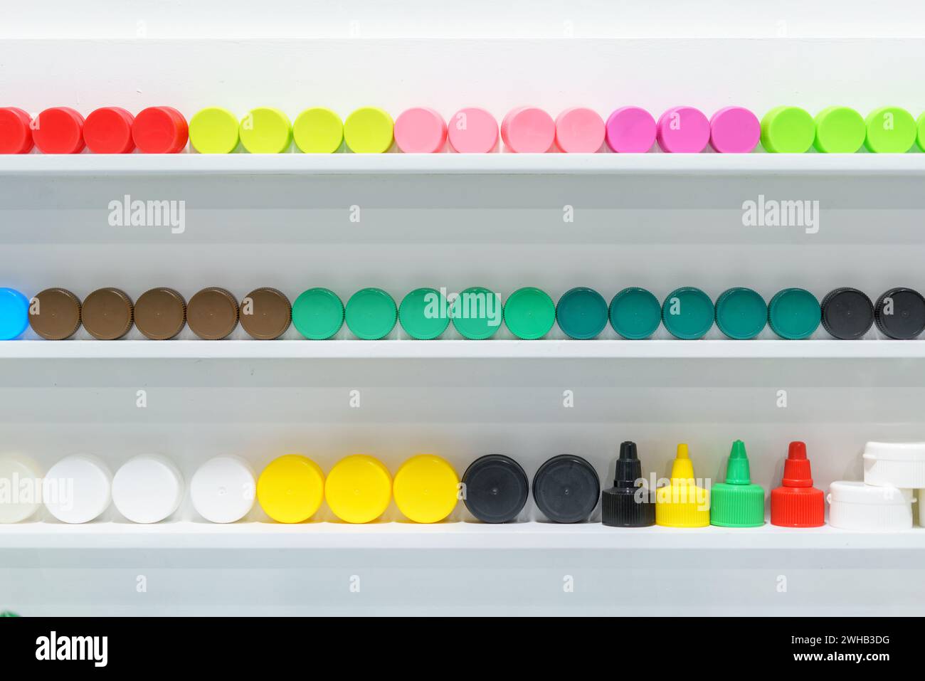 Eine lebendige Kollektion farbenfroher Flaschenverschlüsse, die ordentlich in Regalen angeordnet sind und eine große Auswahl an Farbtönen und Größen zur Inspiration für das Verpackungsdesign zeigen Stockfoto