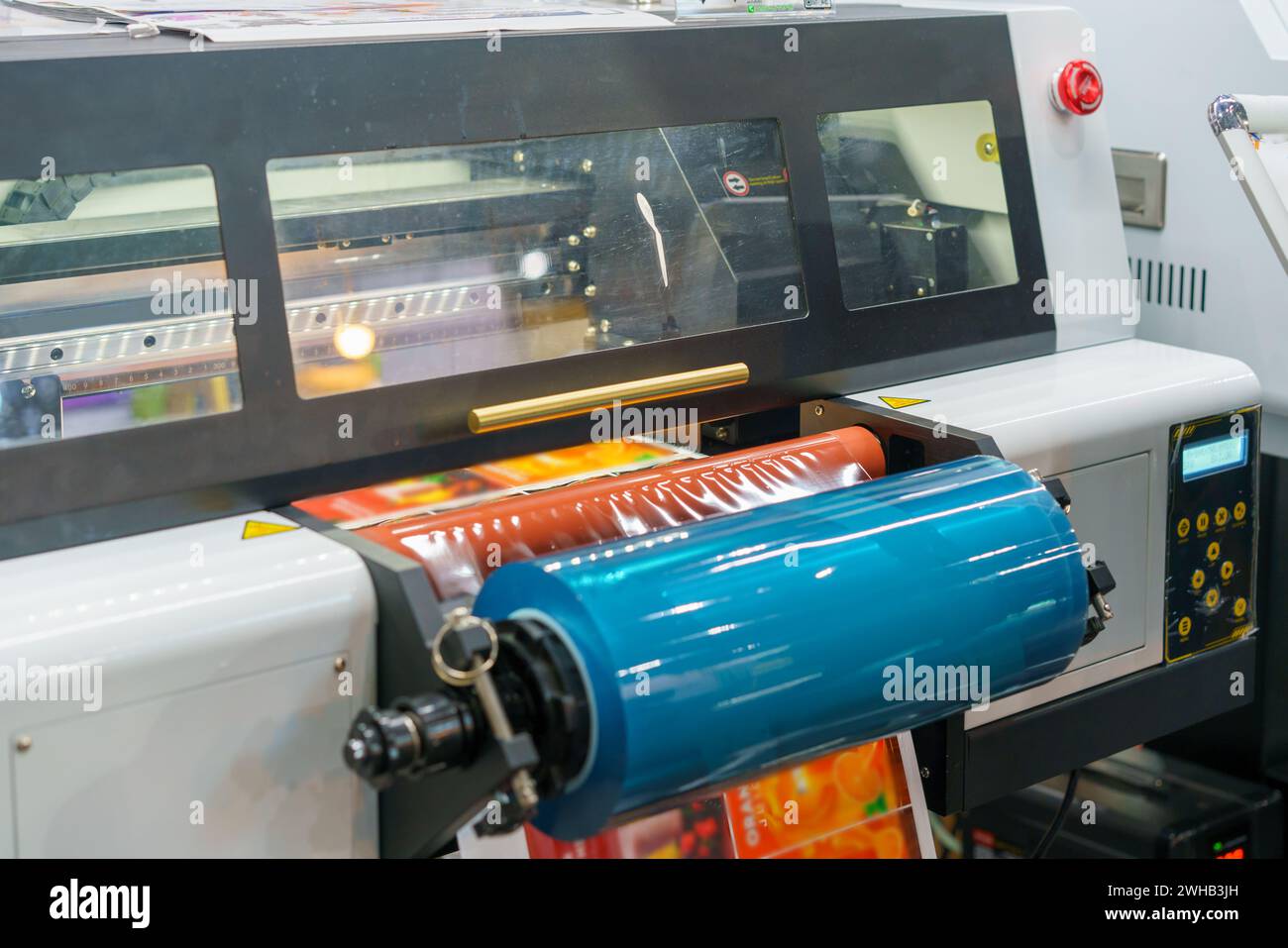 Hochauflösendes Bild, das den industriellen Druckprozess von Klebeetiketten zeigt und die Maschinen und Etikettenbögen in leuchtendem Rot zeigt Stockfoto