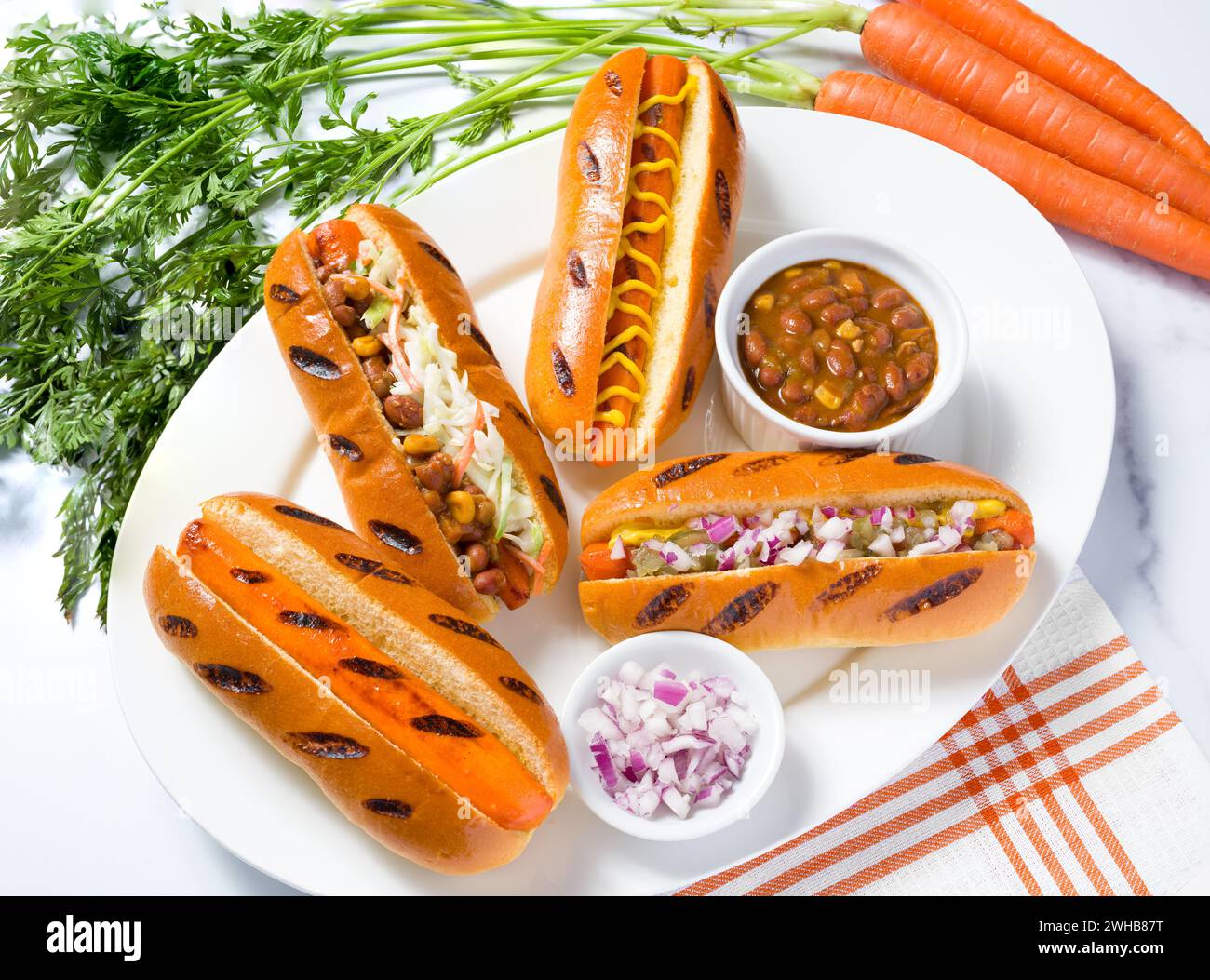 Karottenhunde mit Gewürzen und rohen Karotten auf Marmoroberfläche; pflanzliches Futterkonzept; Fleischalternative Stockfoto