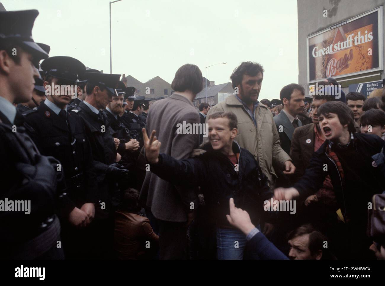 V-Schild, zwei Fingergrüße, Teenager-Jungs geben ihre Wut über passive RUC, Royal Ulster Constabulary Polizisten aus. Die republikanisch-katholischen Demonstranten blockieren eine Straße im Zentrum von Belfast 1981. The Troubles 1980s Northern Ireland UK HOMER SYKES Stockfoto