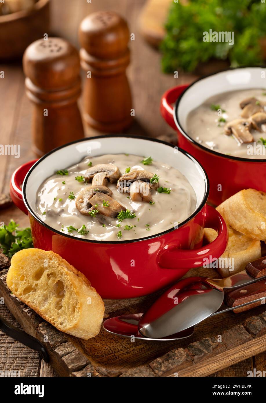 Zwei Schüsseln cremige Pilzsuppe mit Pilzscheiben und Petersilie auf einem rustikalen Holztablett Stockfoto
