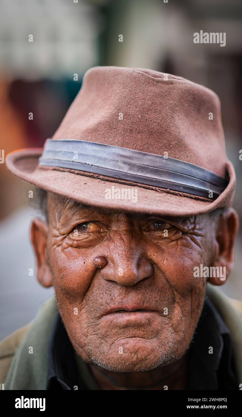 Ein Porträt eines älteren Ladakhi-Mannes, der einen verblassten braunen Hut trägt. Stockfoto