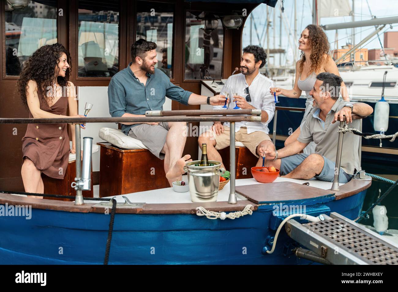 Eine Gruppe von Freunden, die auf einer entspannten Bootstour Drinks und Lächeln teilen. Stockfoto