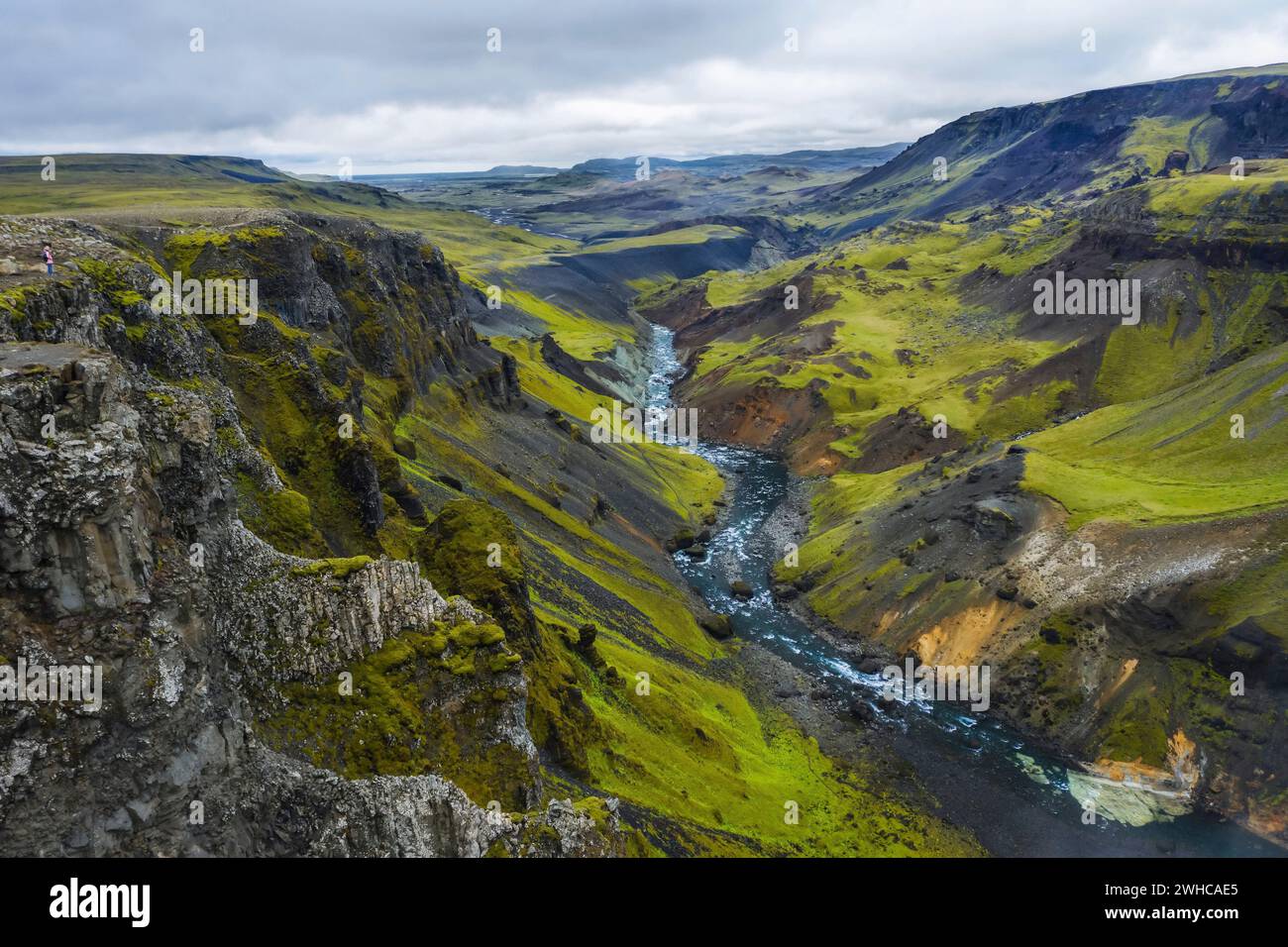 Frau Wanderer genießen die Highlands von Island. Fluss Fossa Strom im Landmannalaugar Canyon Tal. Hügel und Klippen sind von grünem Moos bedeckt. Stockfoto