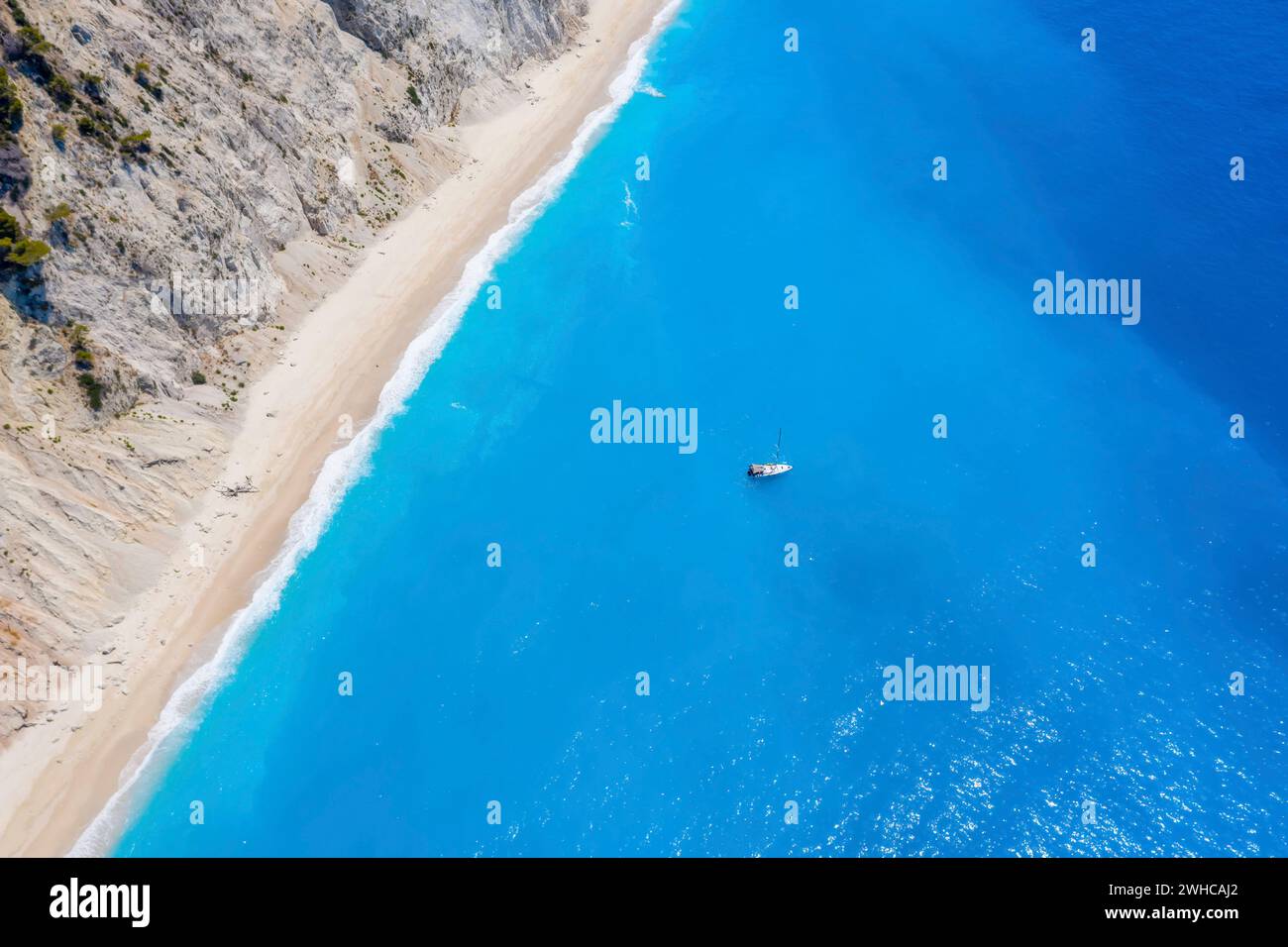 Lefkada, Griechenland. Abgelegener weißer Egremni-Strand mit einsamem Luxus-Yacht-Boot an der türkisfarbenen Bucht am Ionischen Meer. Stockfoto
