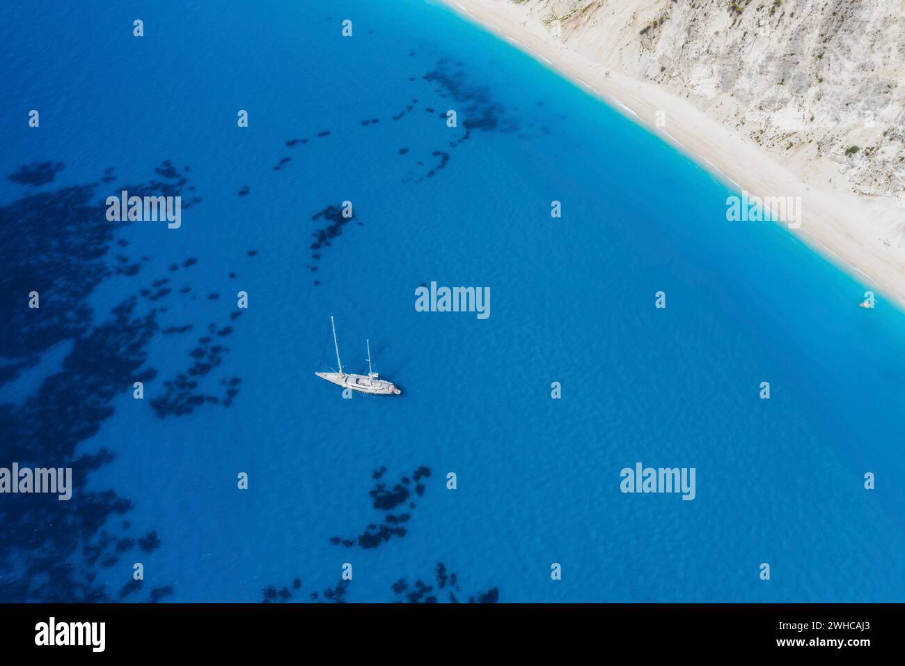 Lefkada, Griechenland. Abgelegener weißer Egremni-Strand mit einsamem Luxus-Yacht-Boot an der türkisfarbenen Bucht am Ionischen Meer. Stockfoto
