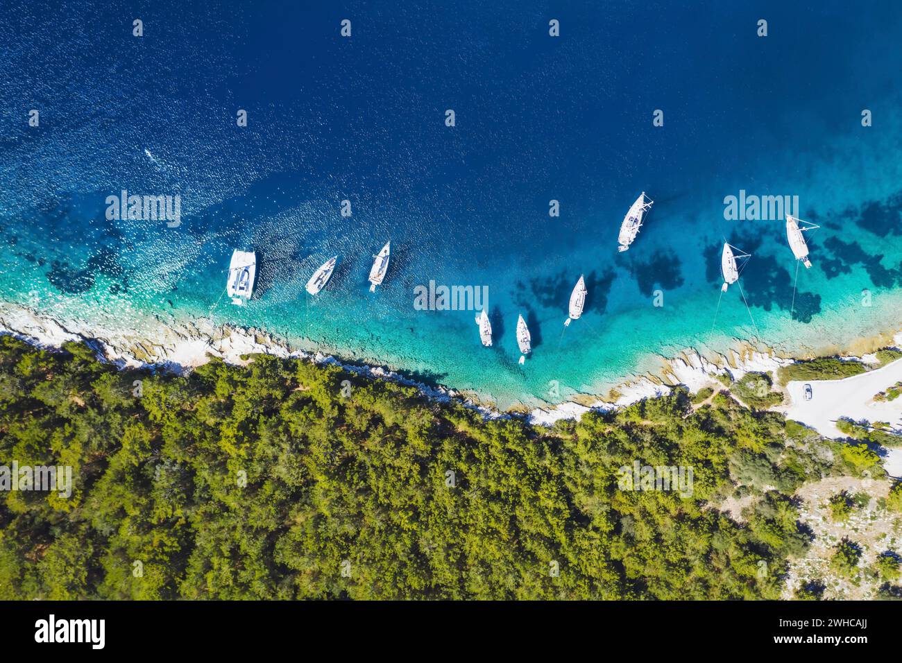 Von oben nach unten sehen Sie Segelboote in der blauen Bucht von Fiskardo, Insel Kefalonia, Ionisches Meer, Griechenland. Stockfoto