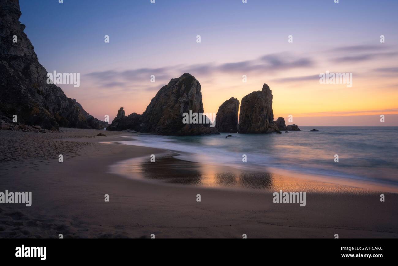 Epic Ursa Beach mit Rock Silhouette und Reflexion gegen goldenen Sonnenuntergang Licht. Cabo da Roca, Sintra an der Atlantikküste in Portugal. Stockfoto