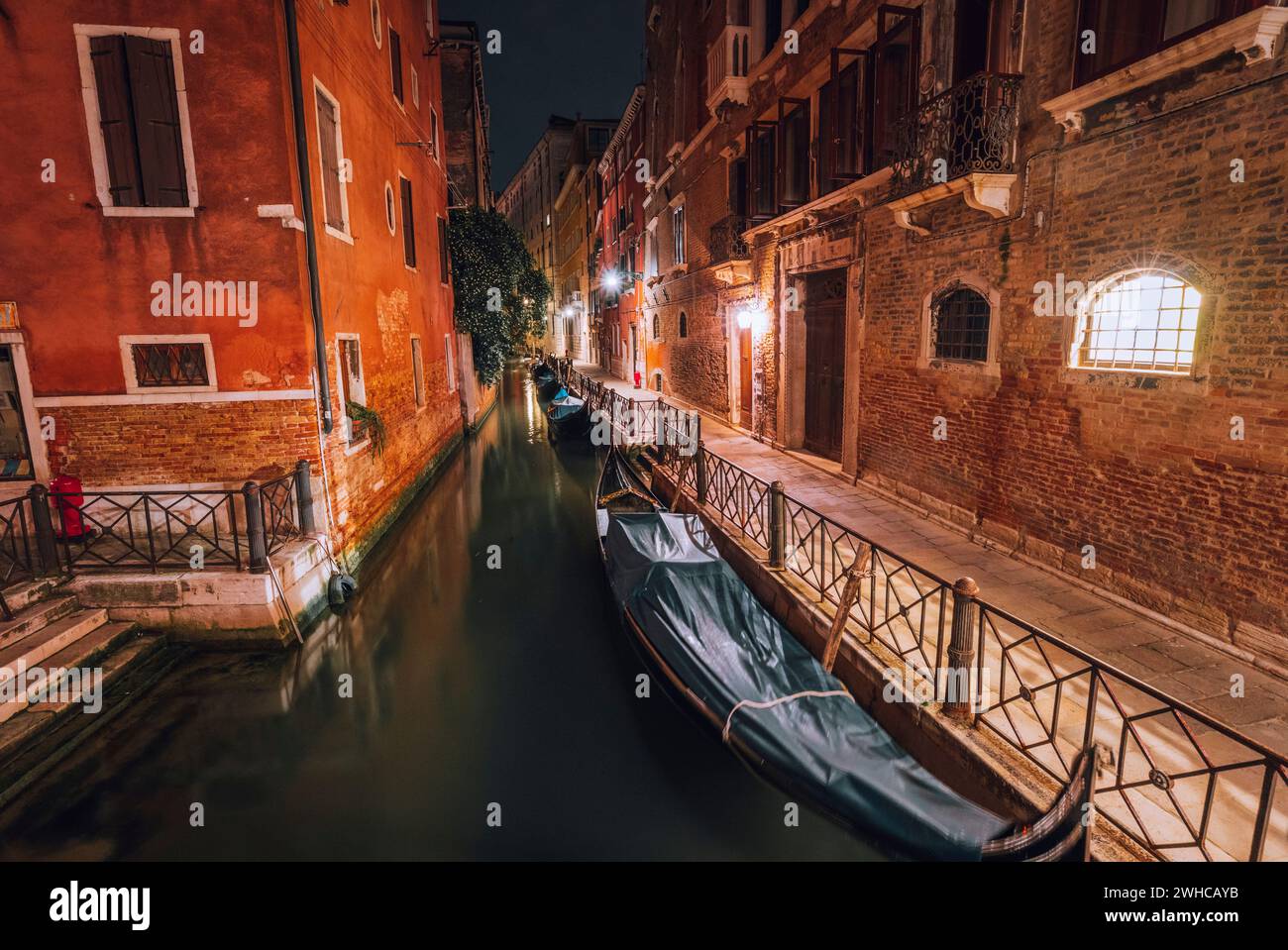 Venezia Italien. Schmaler Kanal und Gondelboote in der Lagunenstadt venedig bei Nacht. Foto mit langer Belichtung. Stockfoto