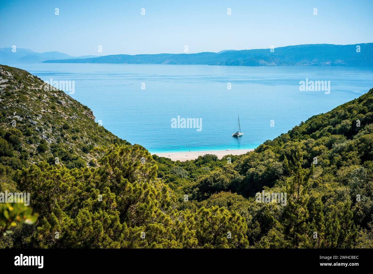 Wanderweg zum weißen Sandstrand, der in der Ferne erscheint, umgeben von mediterraner Vegetation. Fantastische Meereslandschaft Griechenland Ionische Inseln. Sommerabenteuerurlaub. Stockfoto