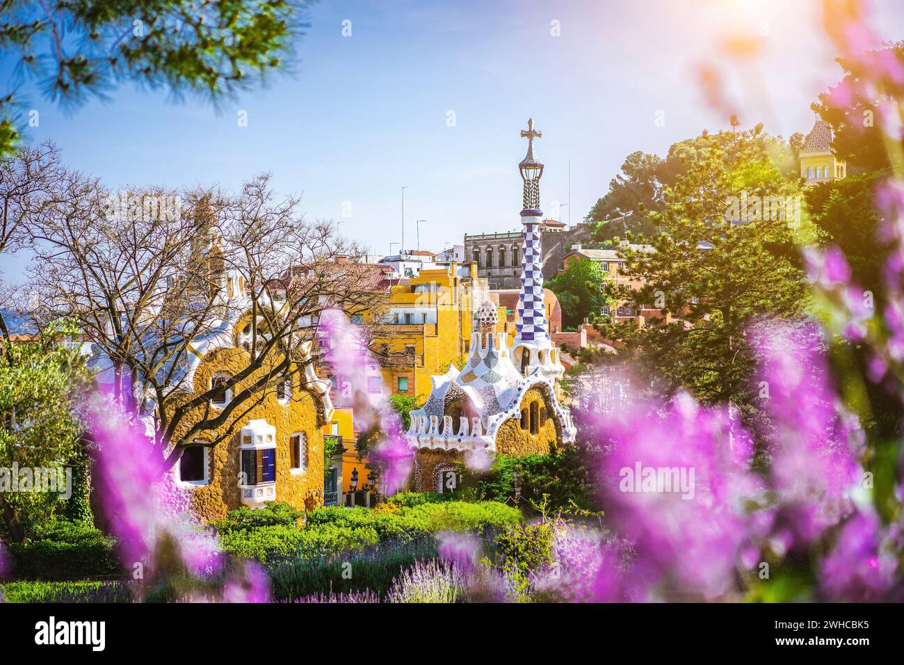 Märchenhaus im Park Güell in leuchtend violettem lavendel Blumenrahmen. Berühmte Lage Sommerwochenende Sonnenuntergang. Das Hotel liegt auf dem Carmel Hill, Barcelona, Spanien. Stockfoto