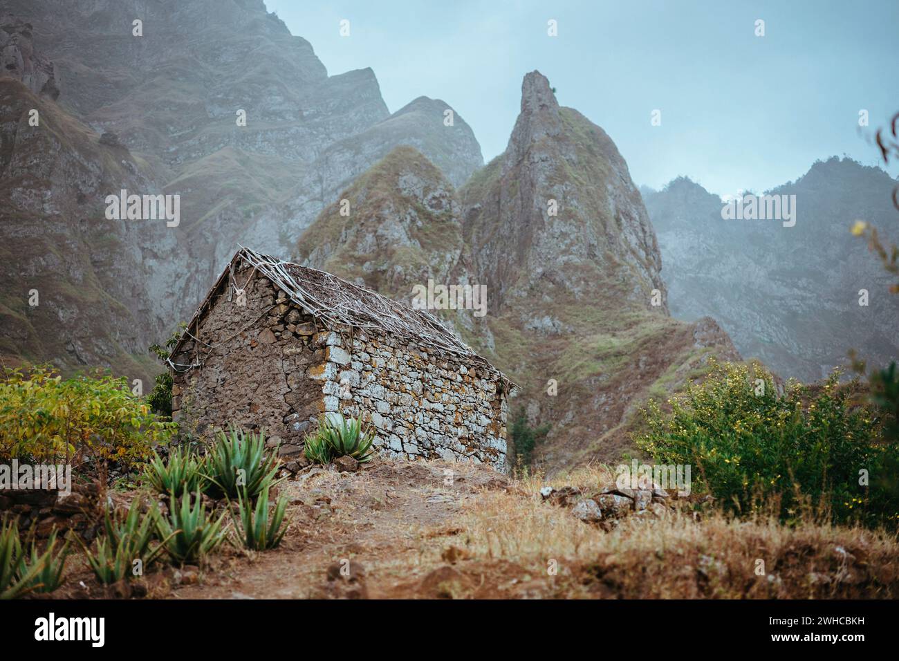 Ruiniertes lokales Lagerhaus eingebettet in eine unglaubliche Landschaft mit steilen Bergfelsen und vertikalen Gipfeln. Trekkingtrail auf Santo Antao Kap Verde. Stockfoto