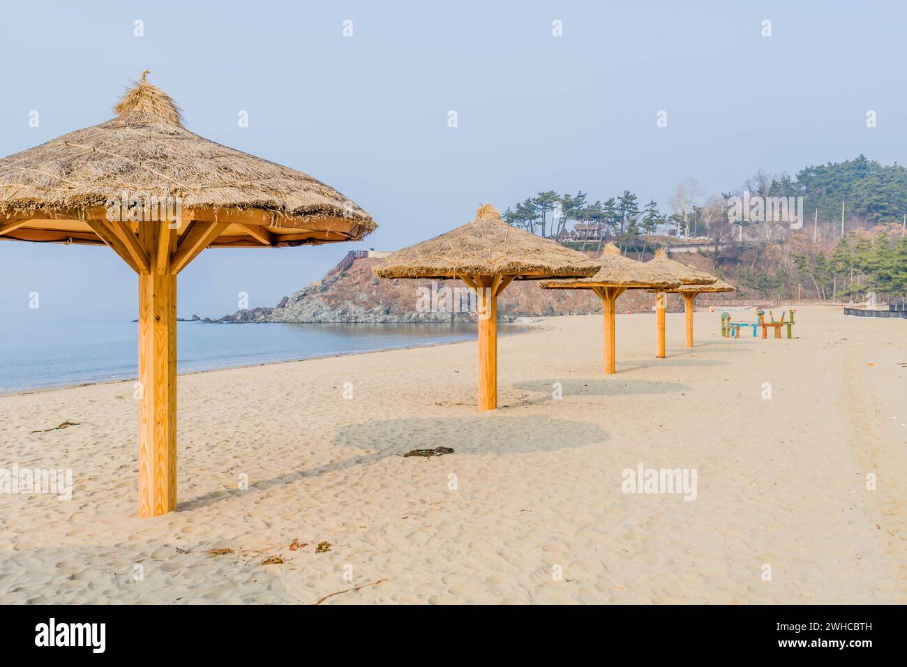 Strohgedeckte, schattige Pavillons am leeren Strand unter grauem Winterhimmel Stockfoto