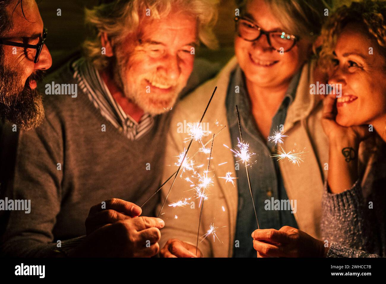 Gruppe von vier Personen wie Senioren und Erwachsene die neue Jahr des neuen Jahres feiern zusammen mit Wunderkerzen und Pizza Stockfoto