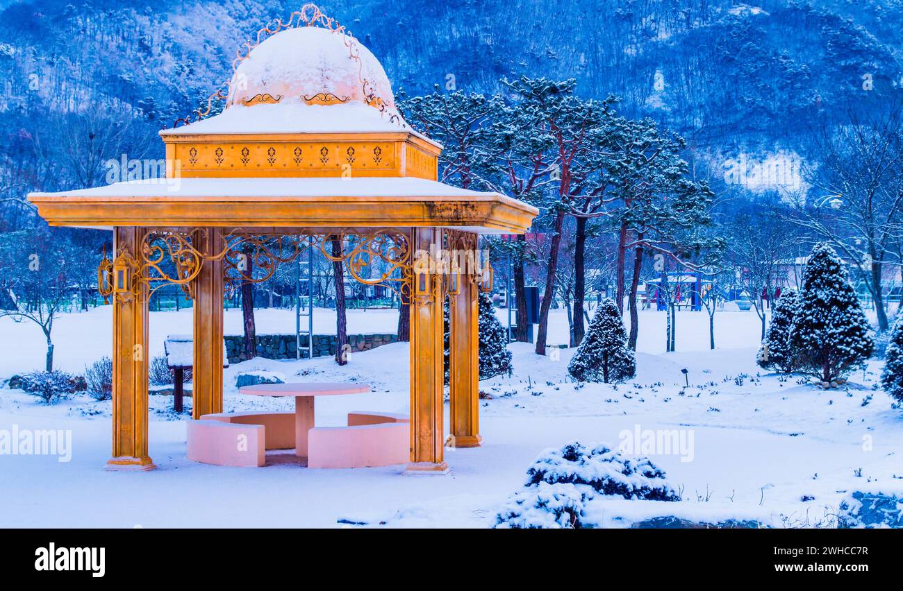 Winterlandschaft eines schönen Pavillons in einem öffentlichen Park bedeckt mit weichem weißen Schnee mit Bäumen im Hintergrund in Südkorea Stockfoto