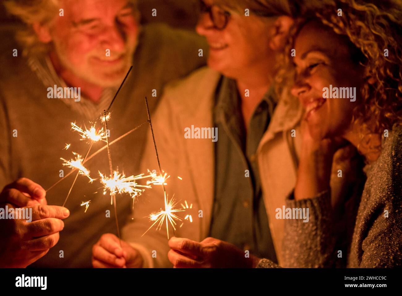Gruppe von Menschen und Familie feiern eine Party oder neu Jahr zusammen auf der Terrasse des Hauses - vier Wunderkerzen in der Mitte zusammen Stockfoto