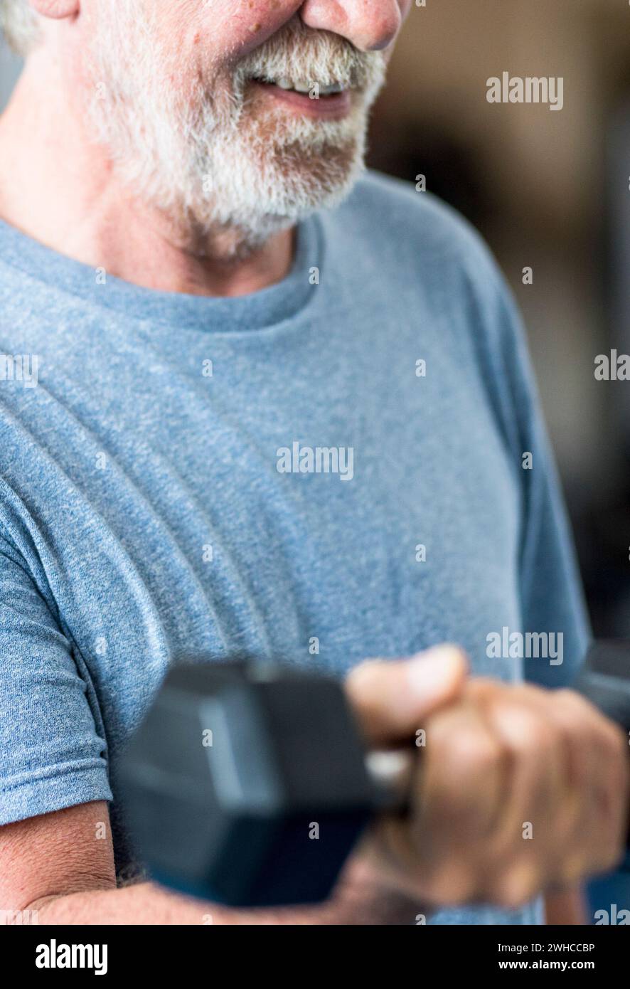 Erwachsener Mann und reifer Senior im Fitnessstudio arbeiten seinen Körper mit Kurzhantel - ein Mann, der gerne drinnen trainiert Stockfoto