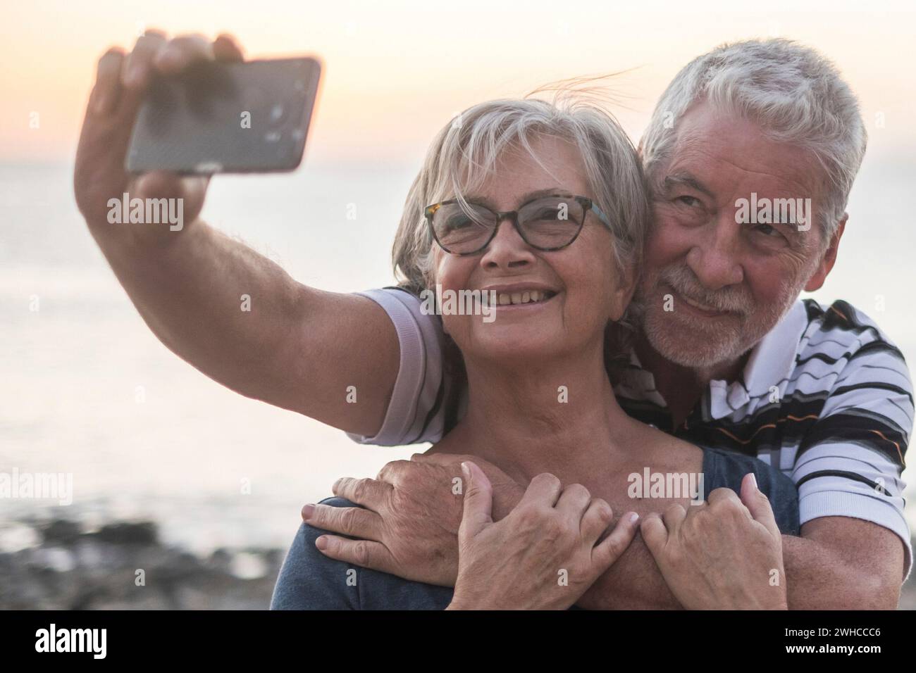 Ein paar Senioren, die einen Salfie am Strand nehmen - ein glückliches verheiratetes pensioniertes Paar genießt es - Frau mit Brille Stockfoto