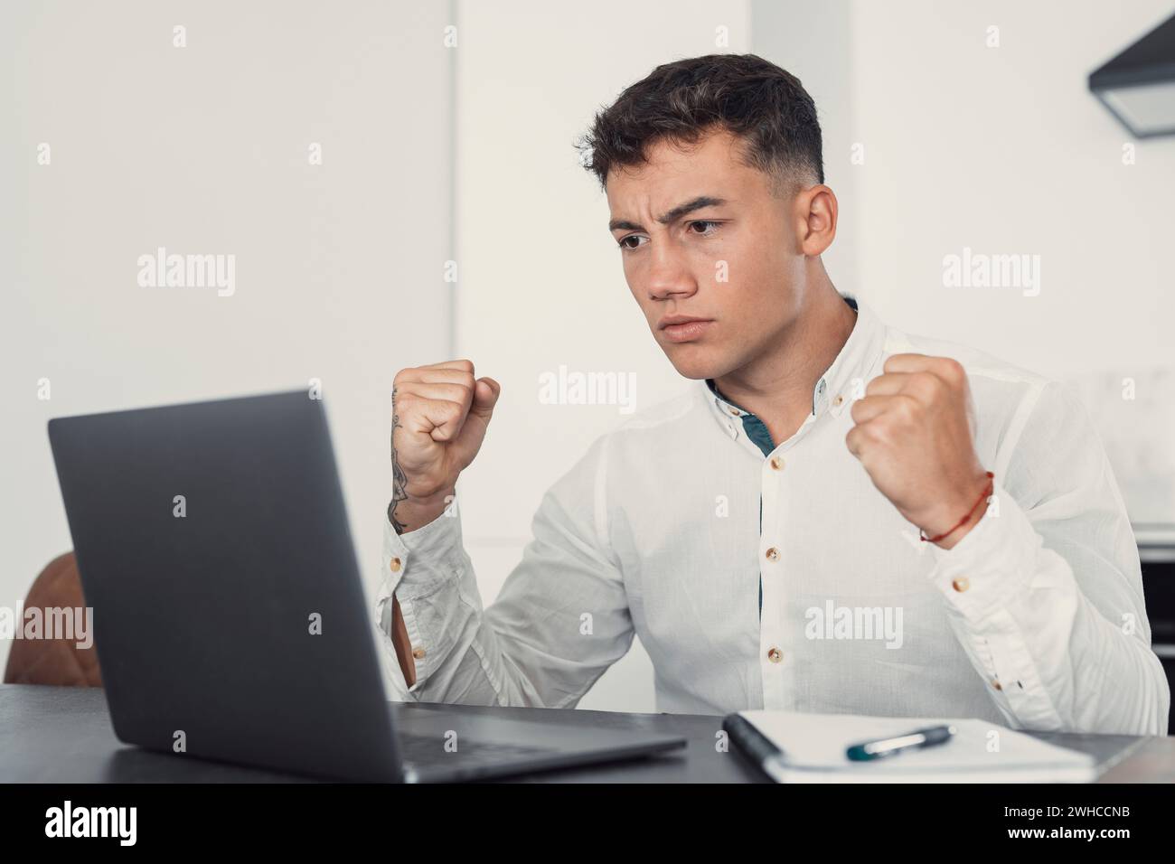 Unglücklicher junger kaukasischer männlicher Arbeiter in Brille schaut auf den Laptop-Bildschirm schockiert von einem Geräteausfall oder Betriebsproblemen. Frustrierter Mann verwirrt von unerwartetem Fehler auf dem Computergerät. Stockfoto