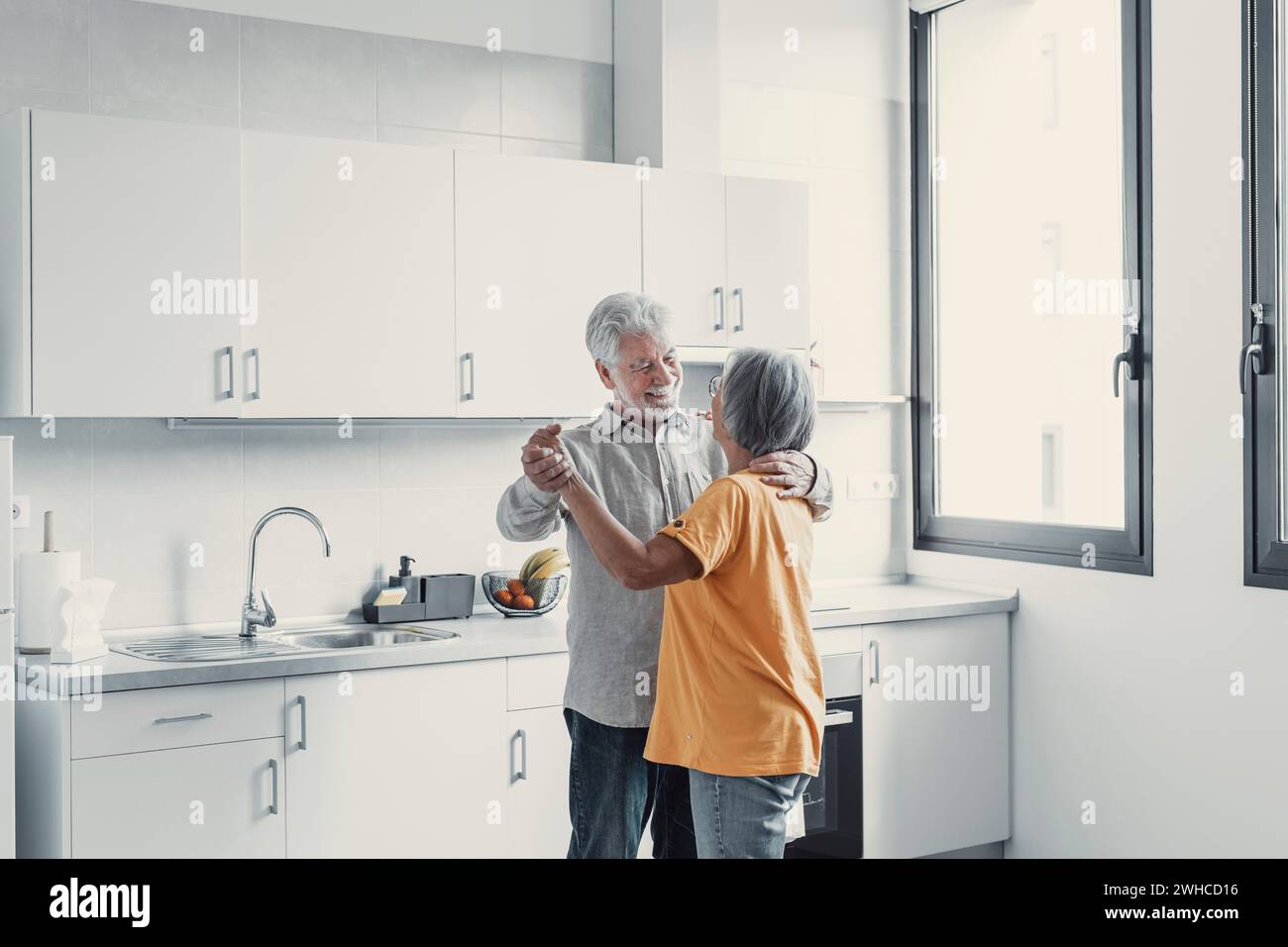 Fröhliches aktives altes, pensioniertes romantisches Paar, das im Wohnzimmer lacht, glückliche Frau mittleren Alters und älterer Mann, die sich zu Hause amüsieren, lächelnde Großeltern der Seniorenfamilie, die sich entspannen Stockfoto