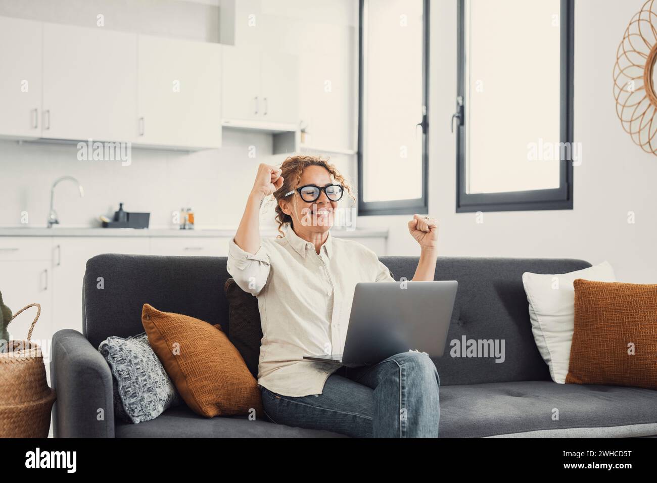 Begeisterte Frau, die auf den Laptop-Bildschirm schaut, vor Freude schreiend, überrascht von Nachricht mit guten Nachrichten, überfröhliche junge Frau, die zu Hause auf der Couch sitzt, Computer benutzt, Online-Gewinn oder -Erfolg feiert Stockfoto
