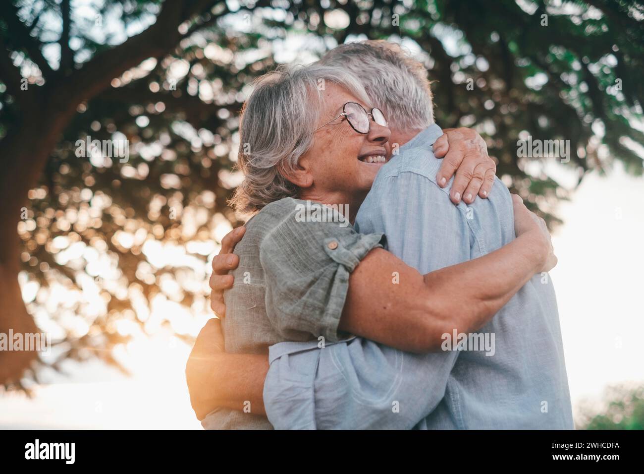 Kopfaufnahme Nahaufnahme Porträt glückliche grauhaarige Frau mittleren Alters, die sich an einen lächelnden älteren Ehemann kuschelt und einen zarten Moment im Park genießt. Ein liebevolles, altes Familienpaar, das sich umschließt, glücklich fühlt. Stockfoto
