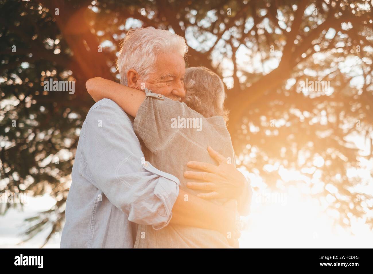 Kopfaufnahme Nahaufnahme Porträt glückliche grauhaarige Frau mittleren Alters, die sich an einen lächelnden älteren Ehemann kuschelt und einen zarten Moment im Park genießt. Ein liebevolles, altes Familienpaar, das sich umschließt, glücklich fühlt. Stockfoto