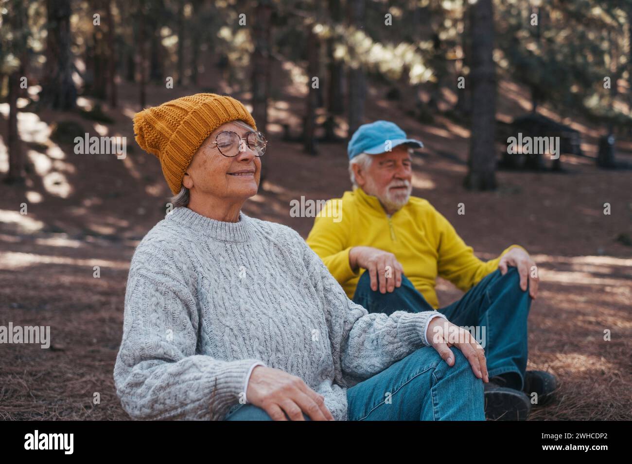 Porträt, Nahaufnahme von zwei älteren Menschen mittleren Alters, die in den Bergen inmitten des Waldes im Freien meditieren und entspannen. Zwei Erwachsene Personen, die Spaß haben, sich zu entspannen. Stockfoto