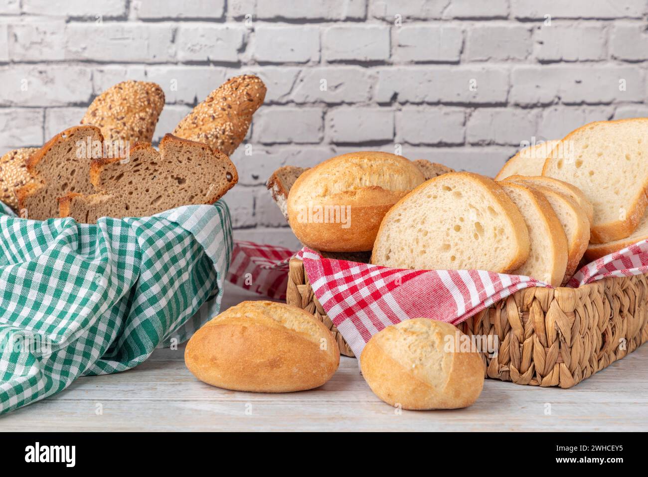 Frisches Gebäck und Brot in zwei Körben vor einer Ziegelmauer Stockfoto