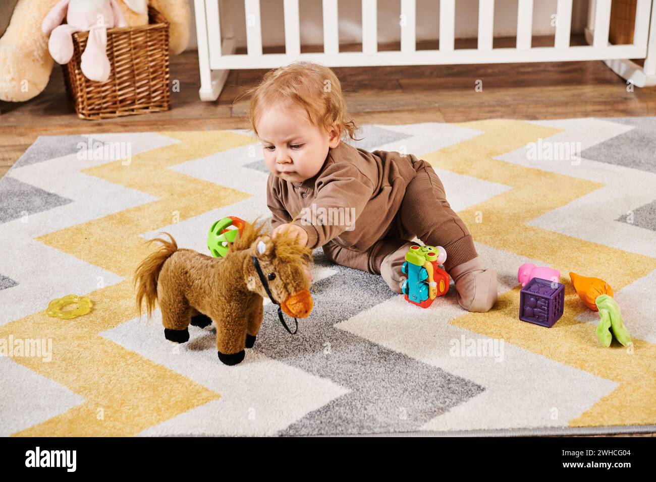 Niedliches Kind, das auf dem Boden sitzt und mit Spielzeug im gemütlichen Kinderzimmer spielt, glückliche Kindheit Stockfoto