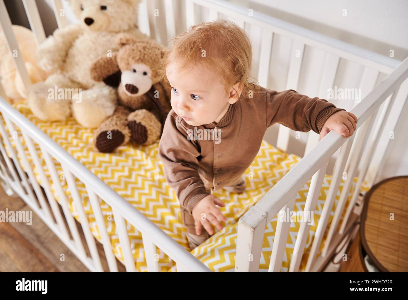 Hochwinkelansicht eines Kleinkindes, der im Kinderbett steht, mit Kuschelspielzeug im Kinderzimmer zu Hause, Kindheit Stockfoto
