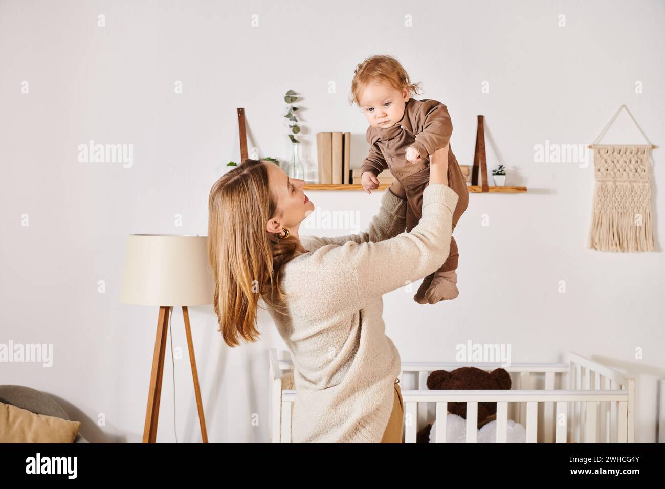 Junge, fröhliche Frau, die mit dem süßen kleinen Sohn im Kinderzimmer spielt und Spaß hat, glückliche Mutterschaft Stockfoto