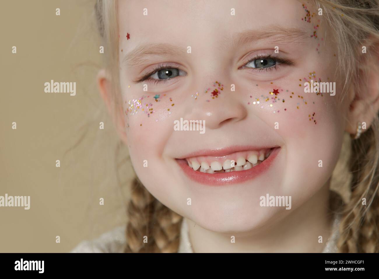 Porträt eines süßen kleinen blonden Mädchens mit blauen Augen und Glitzern im Gesicht. Stockfoto