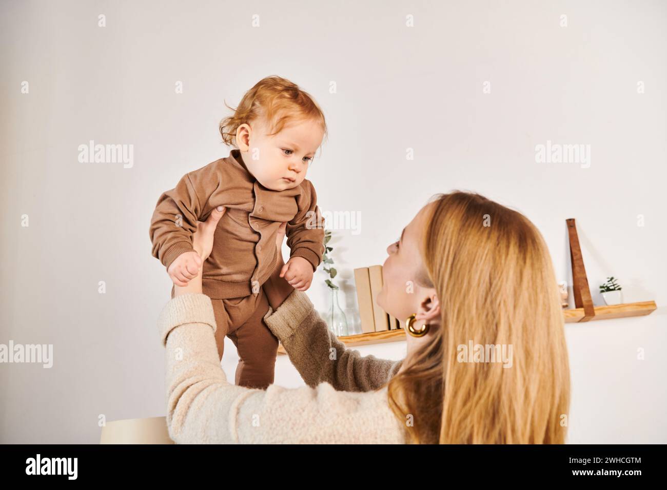 Fröhliche junge Frau, die Spaß hat und mit dem kleinen Sohn zu Hause spielt, glückliche Mutterschaft Stockfoto