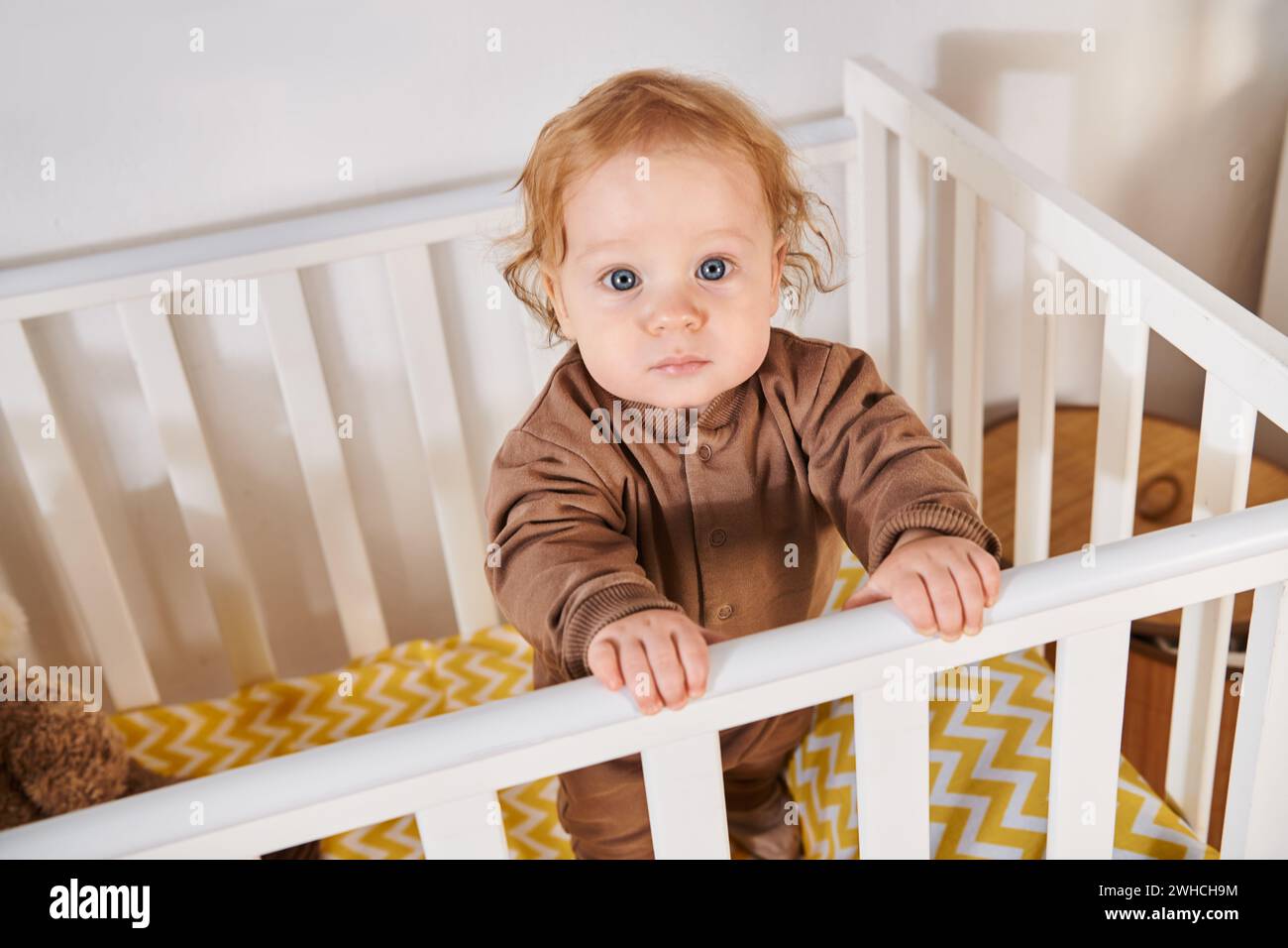 Hochwinkelansicht des liebenswerten Kindes im Strampler, das im Kinderzimmer zu Hause steht, Kleinkind Stockfoto