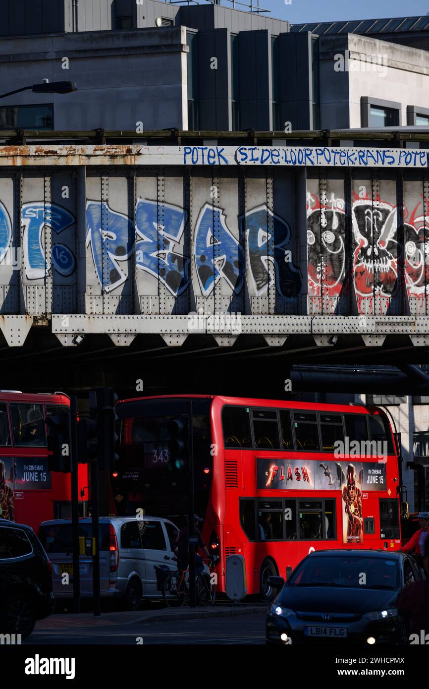 Abendlicher Rush Hour Verkehr, der unter einer graffierten Eisenbahn in der Nähe der London Bridge Station vorbeifährt. Borough High Street, London, Großbritannien. Juni 2023 Stockfoto