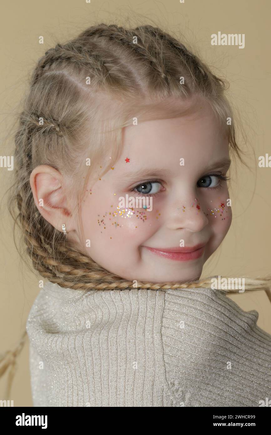 Porträt eines süßen kleinen blonden Mädchens mit Boxerflechten und Glitzern im Gesicht Stockfoto