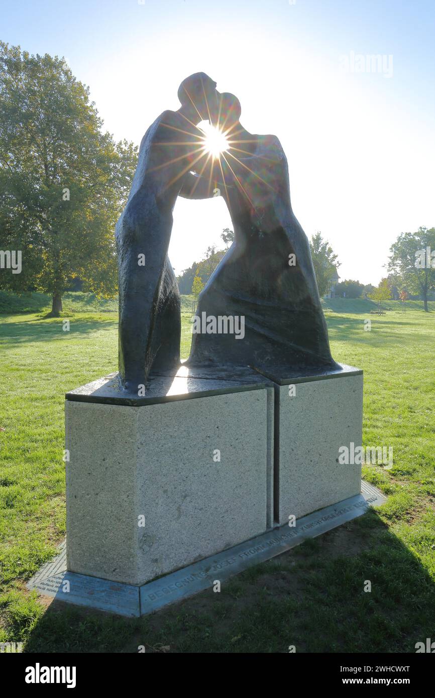 Skulptur Begegnung von Josef Fromm 1994, Hintergrundbeleuchtung, Sonnenstrahlen, zwei, Kontakt, zusammen, umarmen, Figuren, Kommunikation, Waffen, greifen, berühren, Gesten Stockfoto