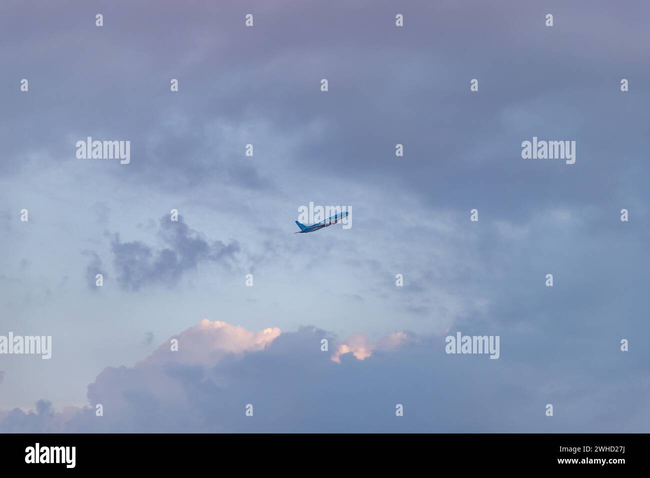 Ein Bild eines Flugzeugs, das bei Sonnenuntergang zwischen den Wolken fliegt. Stockfoto