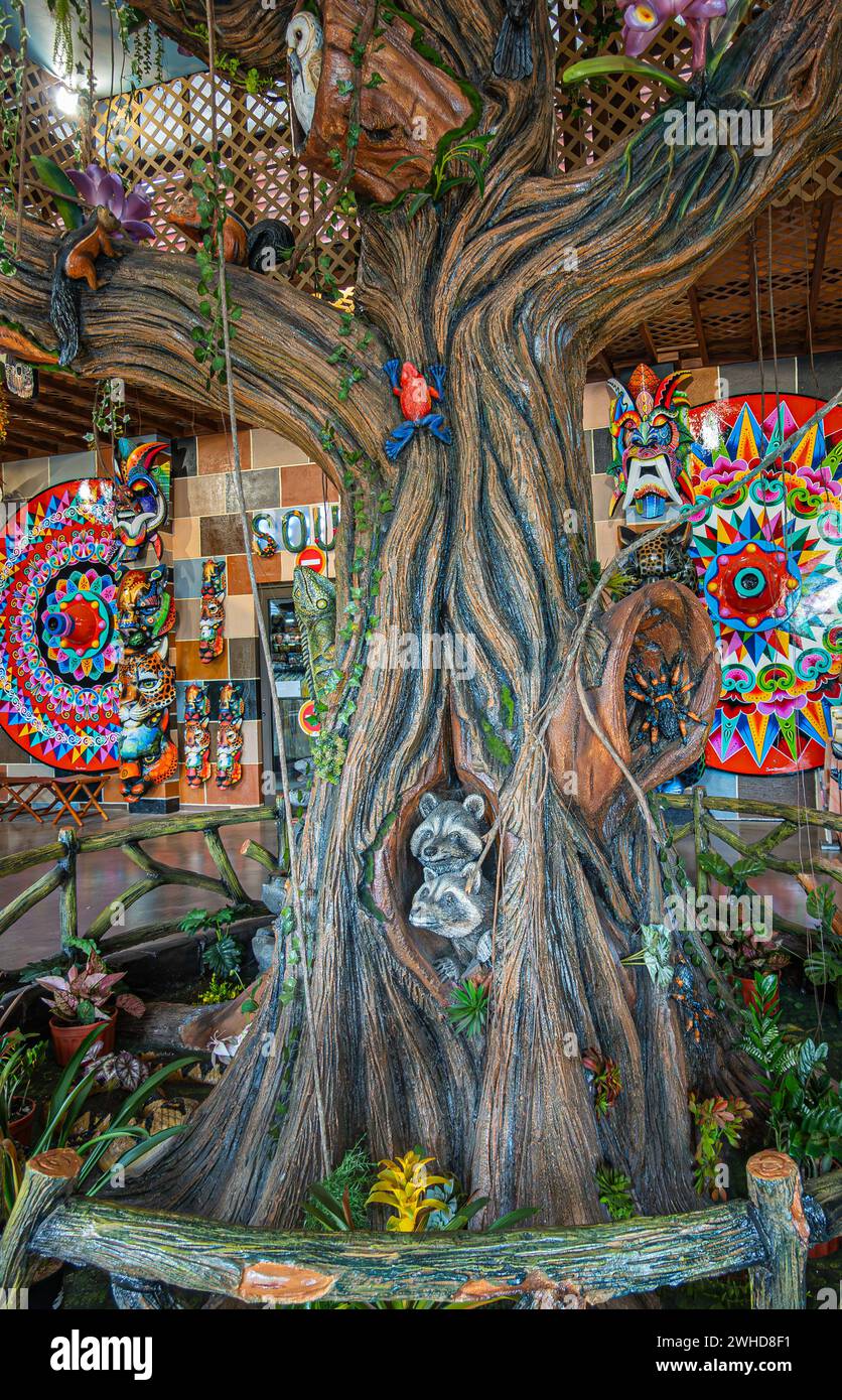 Costa Rica, San Jeronimo - 22. Juli, 20.23: El Jardin Souvenir Shop. Nahaufnahme der dekorierten Holzbaumstatue mit Bildern von Tieren und Vögeln, Backgrou Stockfoto