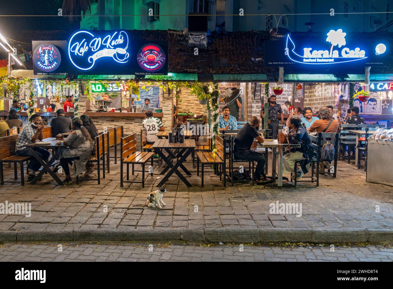 Gäste genießen einen lebhaften Abend in einem Restaurant am Straßenrand an der Tower Road, Fort Kochi, Cochin, Kerala, Indien Stockfoto