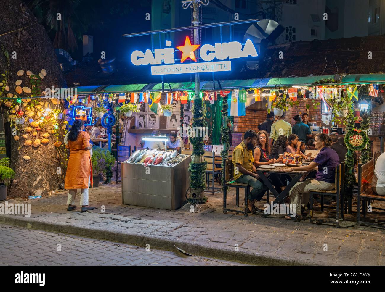 Gäste genießen einen lebhaften Abend in einem Restaurant am Straßenrand an der Tower Road, Fort Kochi, Cochin, Kerala, Indien Stockfoto