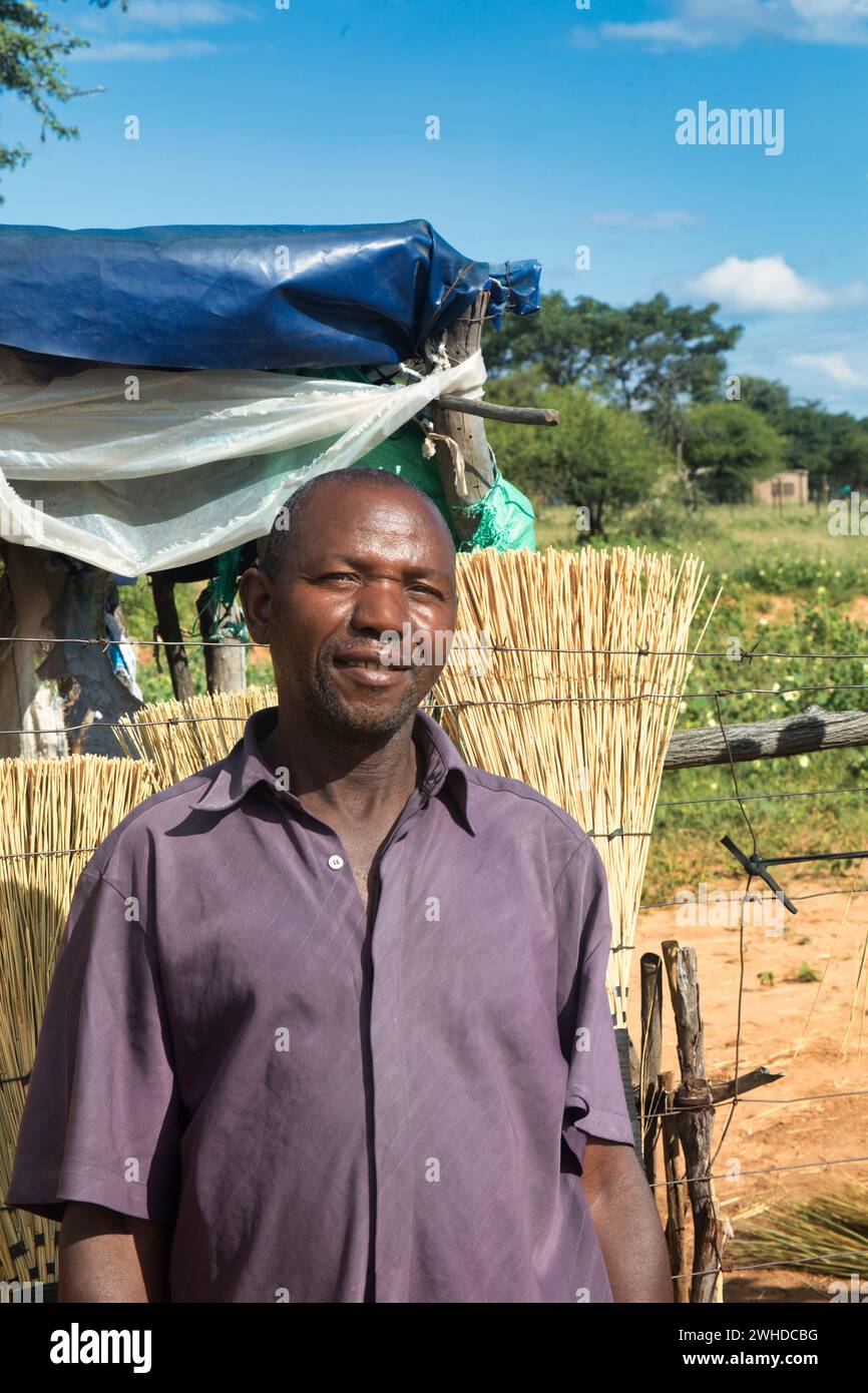 afrikanisches Dorf, Straßenverkäufer, alter Unternehmer, der Besen verkauft, kleines Geschäft Stockfoto